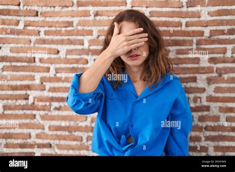 Beautiful Brunette Woman Standing Over Bricks Wall Covering Eyes With