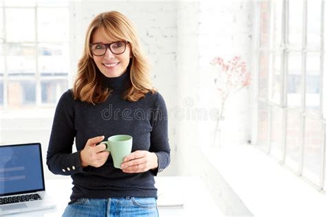 Beautiful Businesswoman Standing In The Office While Drinking Her