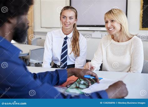 Mother And Teenage Daughter Having Discussion With Male Teacher At High