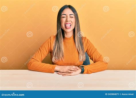 Young Hispanic Woman Wearing Casual Clothes Sitting On The Table