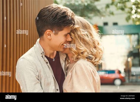 Content Couple Of A Smiling Man Embracing Lovely Blonde Woman In The Street Close Up Outdoor