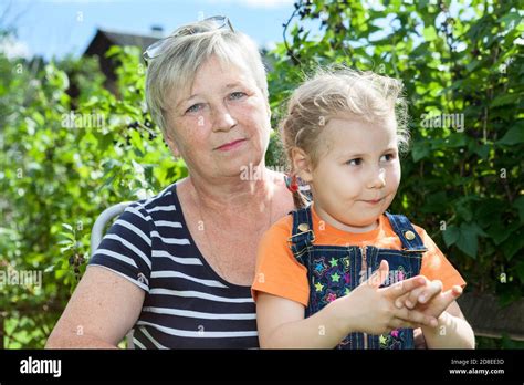 Portrait de la petite fille et de sa grand mère mature en été jardin entre plantes vertes Photo