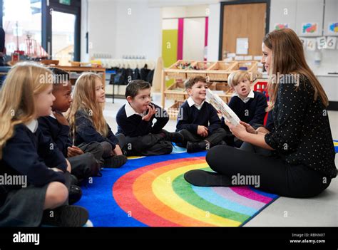 Primary School Kids Sitting On The Floor In Class Listening To Their