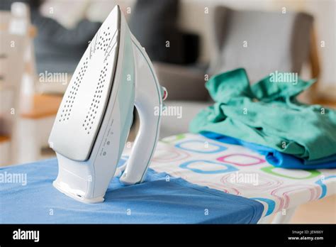 An Iron On An Ironing Board With A Blue Shirt Close Up From The Side