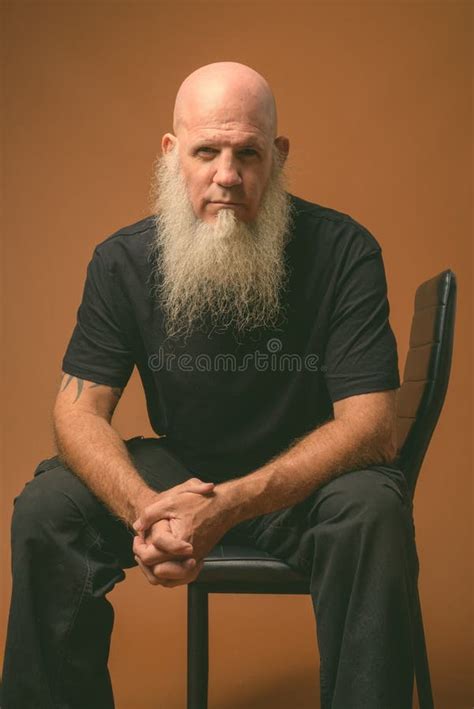 Mature Bald Man With Long Gray Beard Against Brown Background Stock