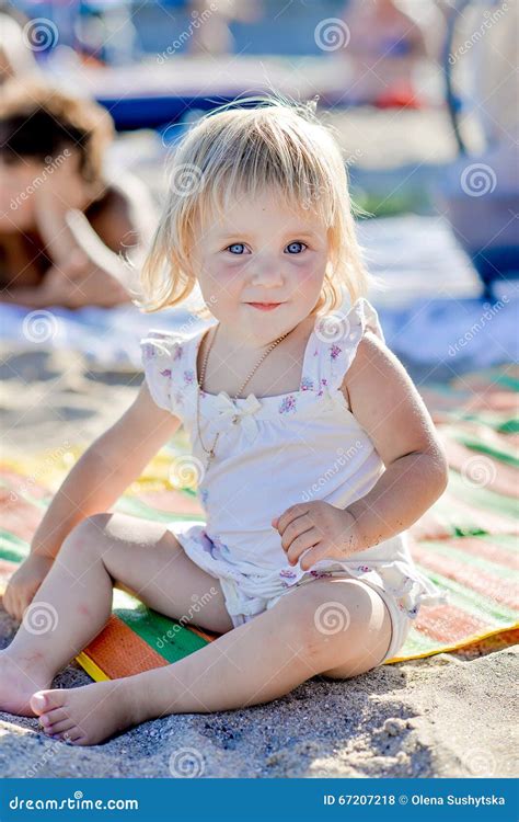 Uma Menina Senta Se Na Praia Na Areia E Sorri Se Foto De Stock Imagem