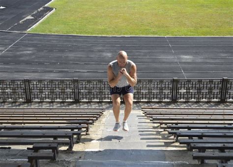 A Bald Man In A Gray T Shirt Trains Jumping On The Steps Of The City