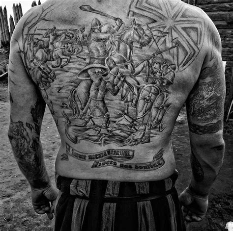 the back of a man with tattoos on his chest and arms, holding a ...