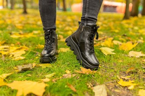 Premium Photo A Woman Wearing Black Boots Stands On The Grass In Autumn