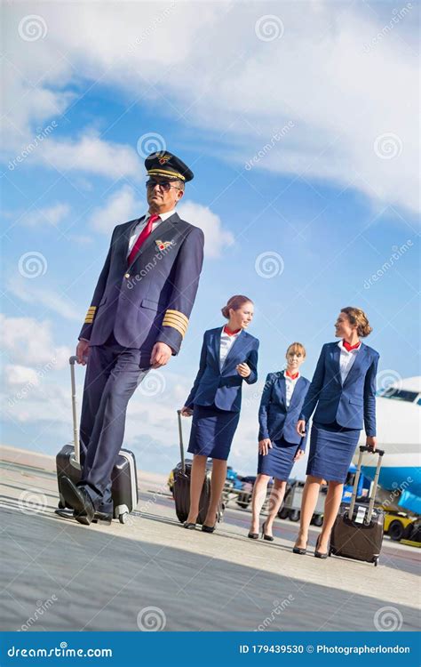 Portrait Of Mature Pilot Walking With Three Young Beautiful Flight