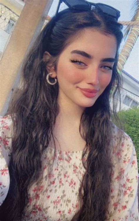 A Woman With Long Hair And Sunglasses On Her Head Taking A Selfie In Front Of A Palm Tree