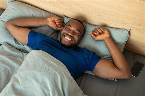 Chico africano alegre que se extiende después de dormir acostado en la