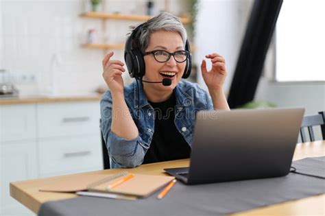 Happy Mature Woman In Headphones In Front Of A Laptop Gives An Online Lesson Training Stock