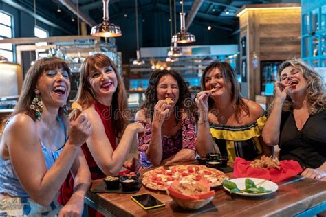 Group Of Mature Women Sitting In A Pub While Eating Pizza Stock Image