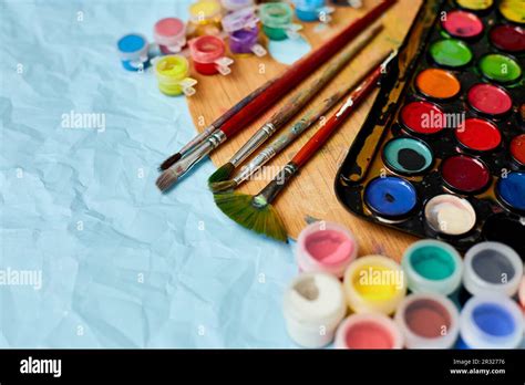 Flat Lay Of Colorful Paints Painting Palette And Brushes On Blue