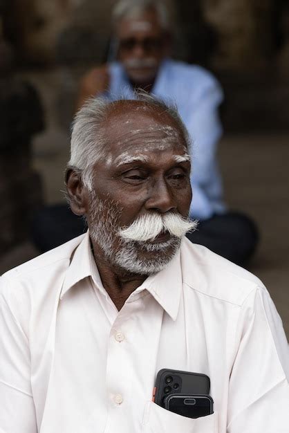 Un Hombre Con Bigote Blanco Se Sienta Frente A Un Templo Foto Premium