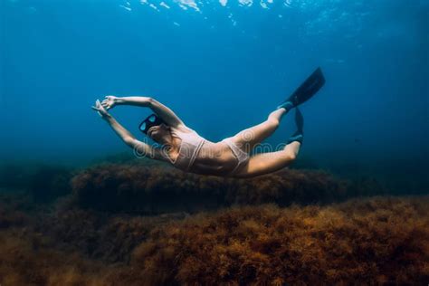 Sporty Woman Freediver With Fins Glides Underwater In Blue Sea Stock