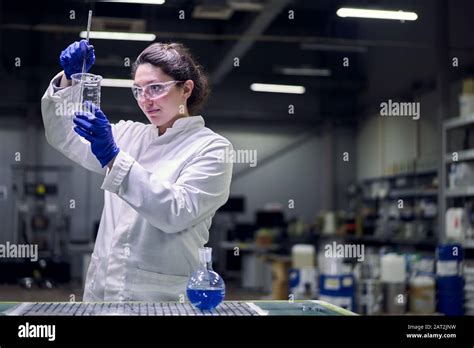 Brunette Lab Girl In Glasses And White Coat With Experimental Glass In