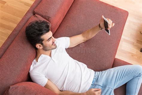 A Happy Young Man Laying On A Sofa And Taking A Selfie Stock Image