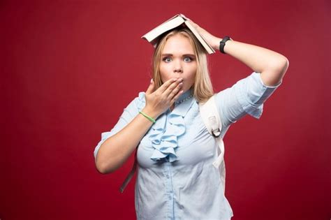 Une Jeune étudiante Blonde Tient Son Livre à La Tête Et A L air Fatiguée Et Confuse Photo