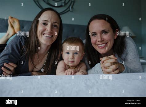 Portrait Of Happy Lesbian Mothers With Son Lying On Bed Stock Photo Alamy