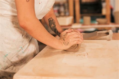 Free Photo An Elevated View Of Female Kneading The Clay On Wooden Table