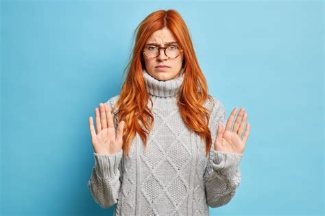 Free Photo Serious Displeased Redhead Woman Shows Stop Gesture Raises Palms Towards Dressed In