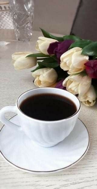 A Cup Of Coffee And Some Flowers On A Table