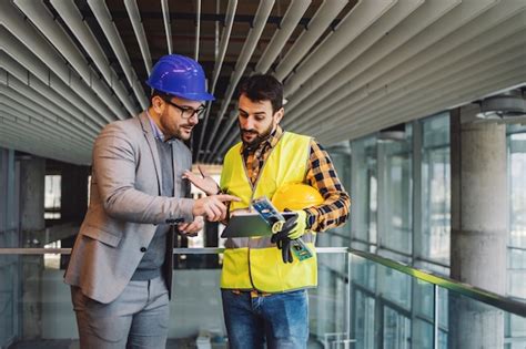 Arquitecto y trabajador de la construcción de pie en el edificio en