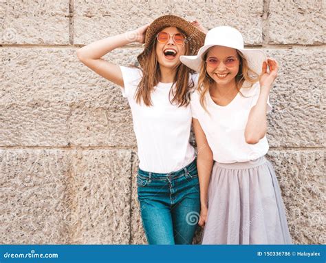 Twee Jonge Glimlachende Hipster Blonde Vrouwen In Kleren Van De De Zomer De Witte T Shirt Stock
