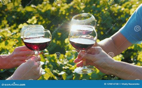 A Group Of Friends Clink Glasses With Red Wine On The Background Of The