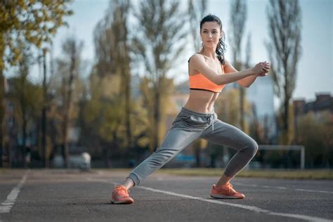 Attractive Brunette Woman Warm Up And Stretching In Park At Sunshine Stock Photo By Goami 275944618