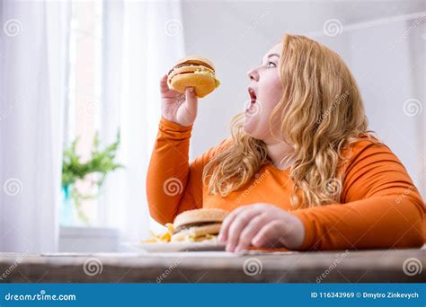 Grosse Femme Satisfaite Mangeant Des Fritures Et Des Sandwichs Image