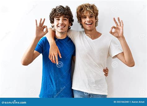 Pareja Joven Gay Parados Juntos En Un Entorno Aislado Sonriendo Positivo Haciendo Un Buen Signo