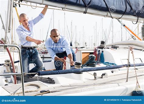 Two Men In Blue Shirts And Jeans Working On Sailing Yacht In The Port Stock Image Image Of