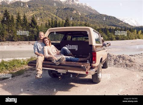 Couple Sitting On Back Of Pick Up Truck Looking At Camera Wallgau Bavaria Germany Stock