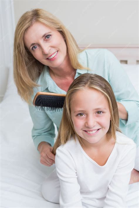 Premium Photo Smiling Mother Brushing Her Daughters Hair