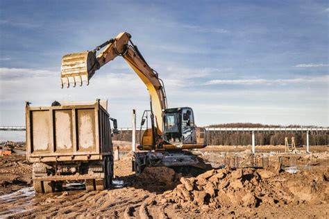 Uma escavadeira carrega um caminhão basculante solo e areia a