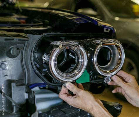 Car headlight in repair close-up. The car mechanic installs the lens in ...