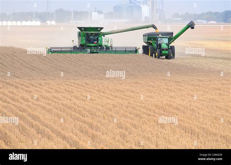 A John Deere Combine Harvesting Soybeans Followed By A John Deere