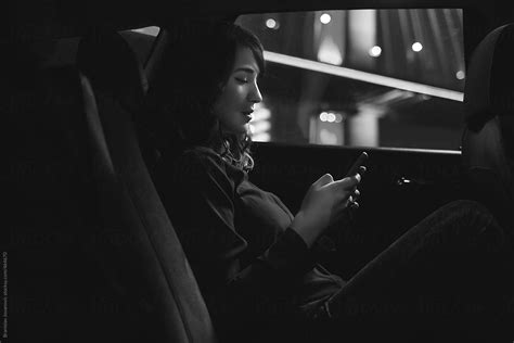 Woman Sitting In The Backseat Of A Car And Using Phone Del Colaborador De Stocksy Brkati