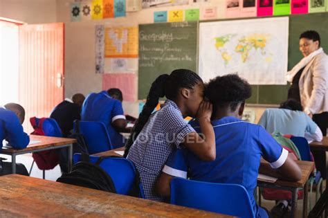 Rear View Of Two Young African Schoolgirls Sitting At Their Desk