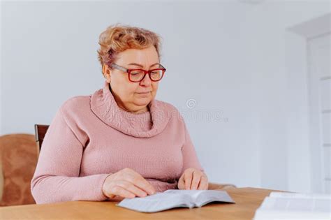 A Candid Shot Of A Plus Size Woman Wearing Glasses And Reading A Book