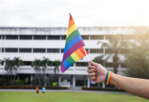 bandera del arco iris en la mano de un gay asiático que usa una pulsera