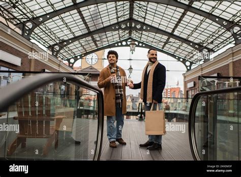 pleine longueur d un couple gay tendance avec des sacs de shopping et du café à aller en tenant