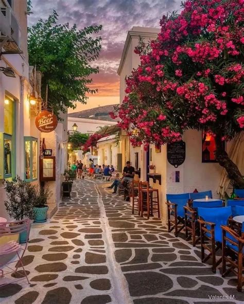 An Alley Way With Tables And Chairs Lined Up Along The Side Of It At Dusk