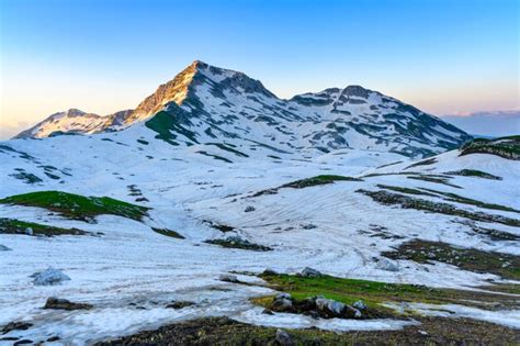 Premium Photo The Snowdrifts And Green Grass On Top Of Mountains In