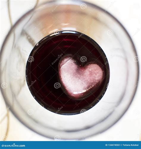 Ice Cube In The Form Of A Heart In A Glass Of Red Wine Stock Photo