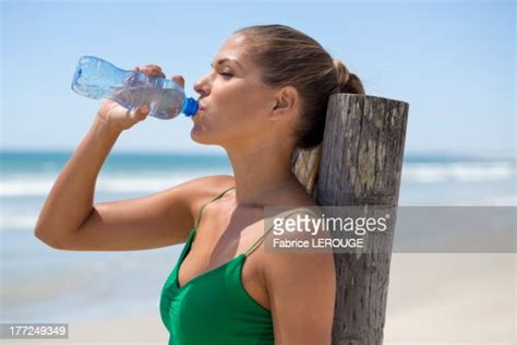 Woman Leaning Against A Wooden Post On The Beach Drinking Water High