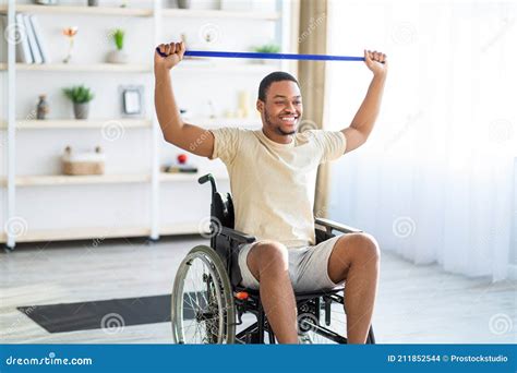 Happy Black Disabled Man In Wheelchair Doing Exercises With Rubber Band